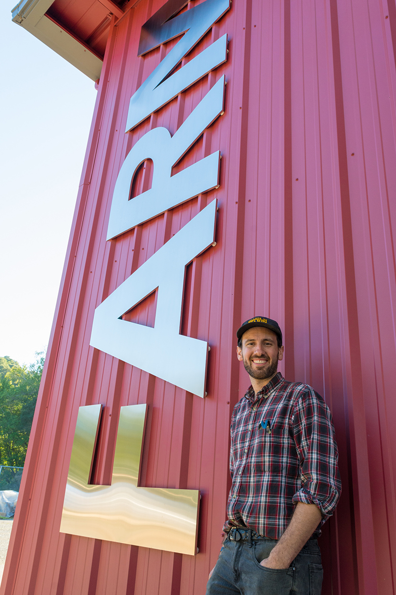 Johnny Campbell stands in front of the farm building