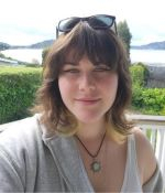 Student wearing gray sitting in front of greenery and lake