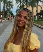 Student in yellow in front of palm trees